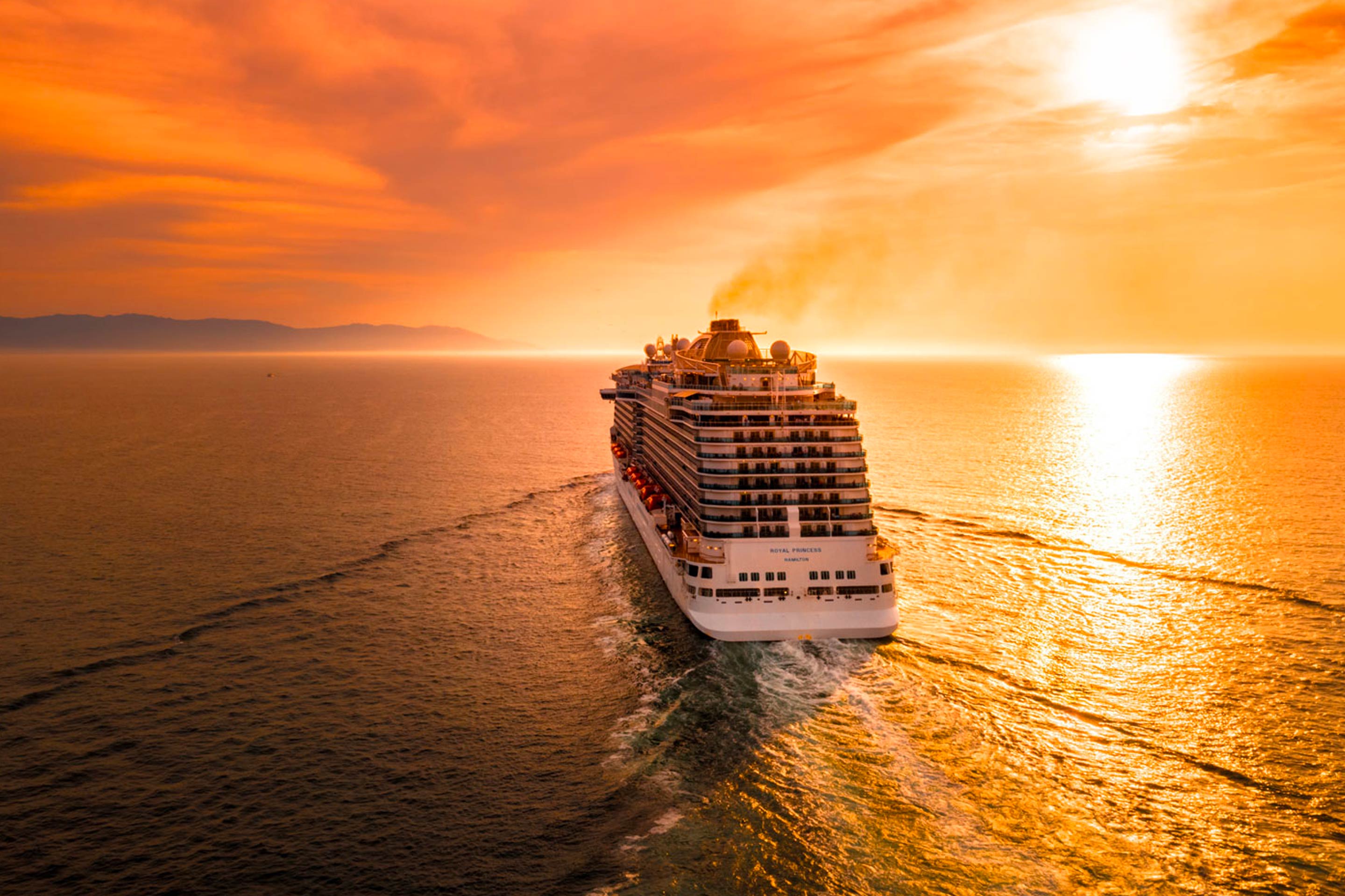 A ship at sea with a sunset background